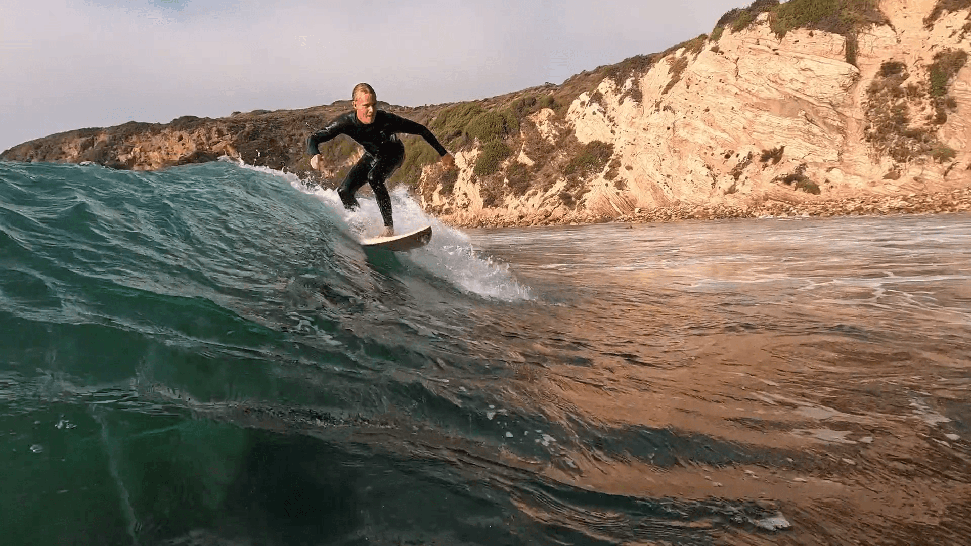 A young man surfing on the Malibu coastline.